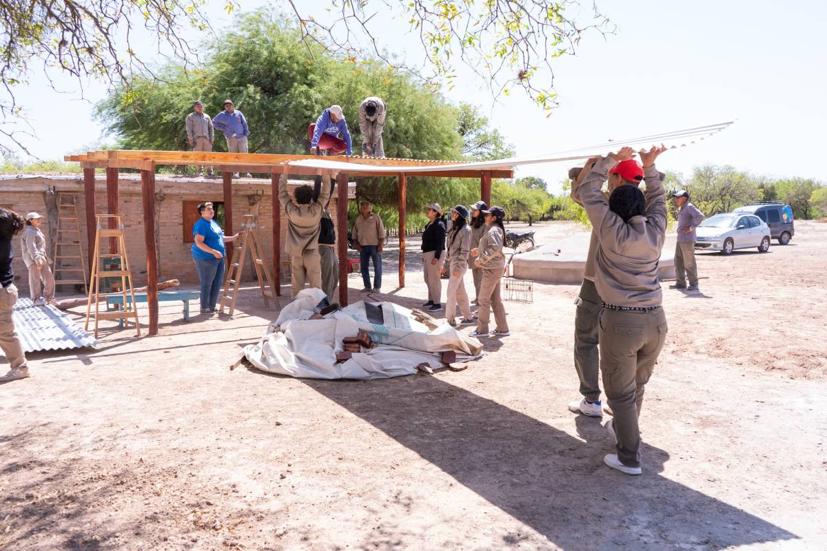 Volunteers installing roofing sheet for rainwater system in community