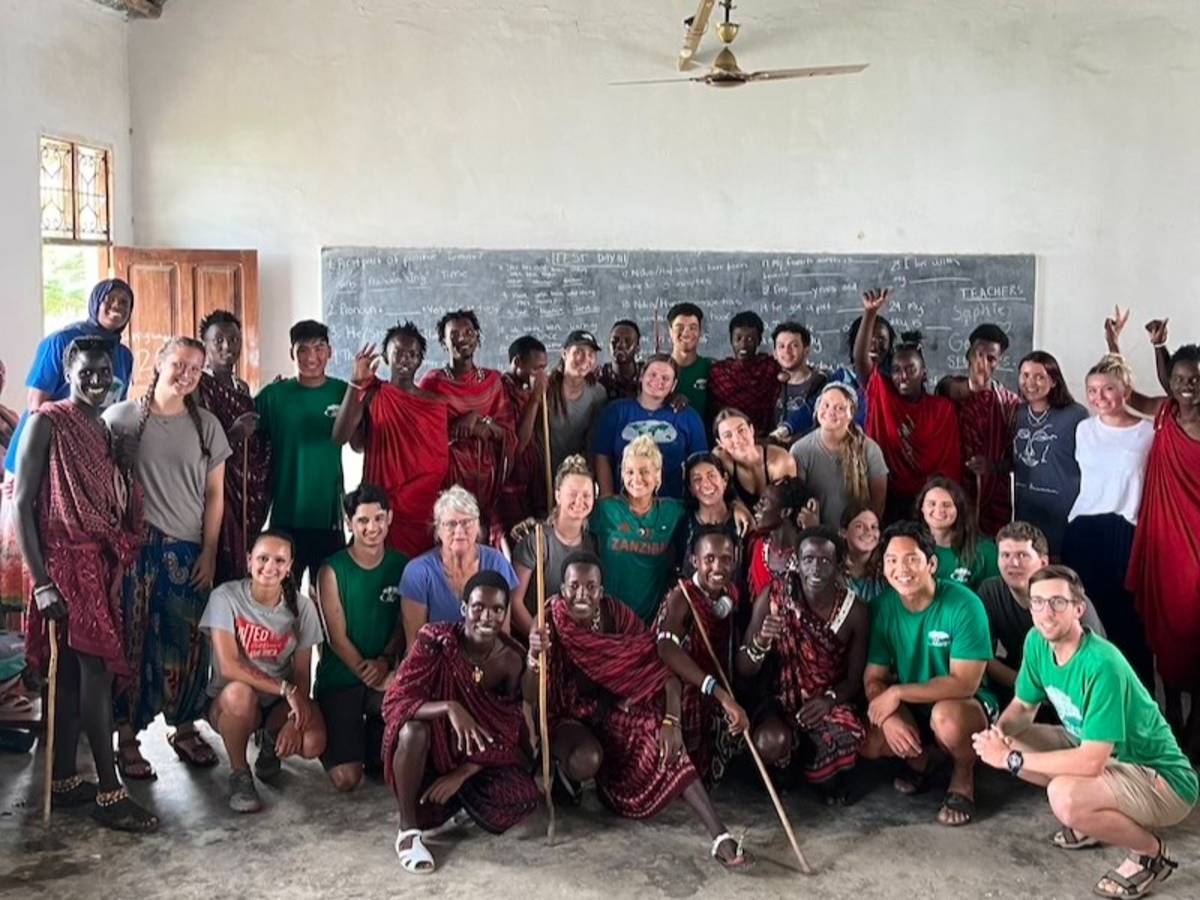 Volunteers with local students in rural Tanzania teaching English
