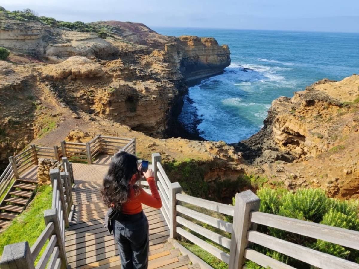Woman taking a photo of the sea and cliffs