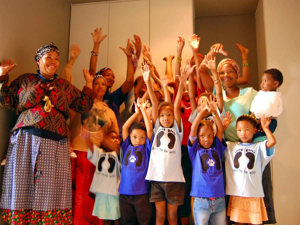 Woman with a group of children raising their hands in Namibia