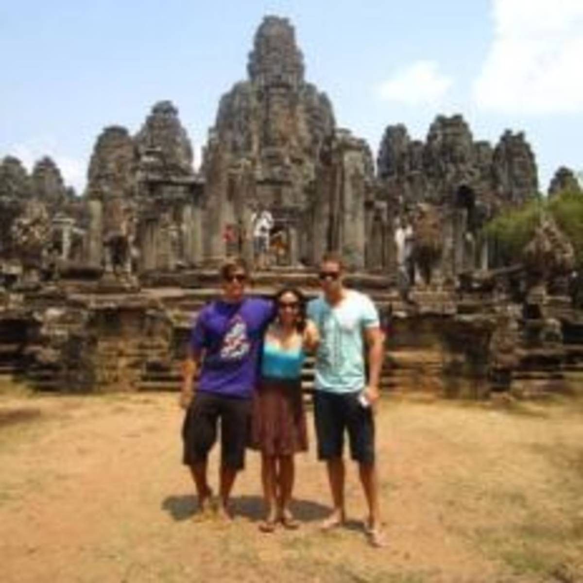 3 people posing in front of ancient Thai Temple