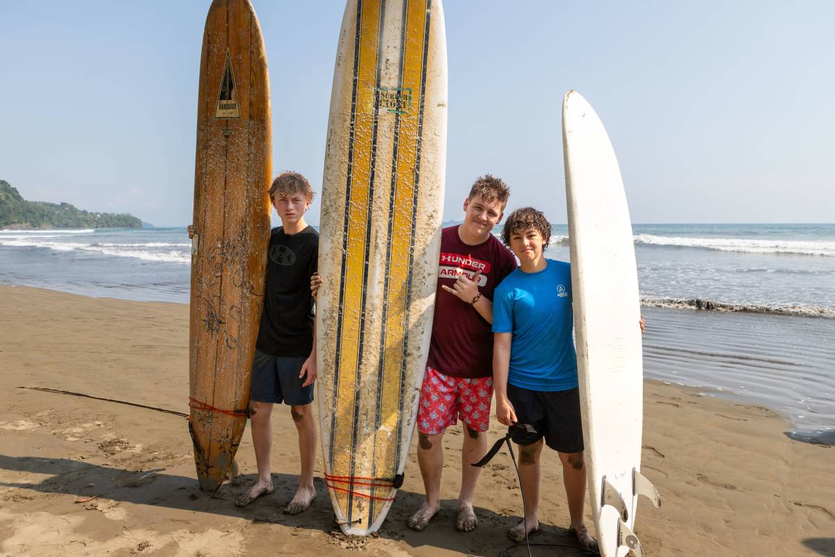 3 young men pose with surfboards