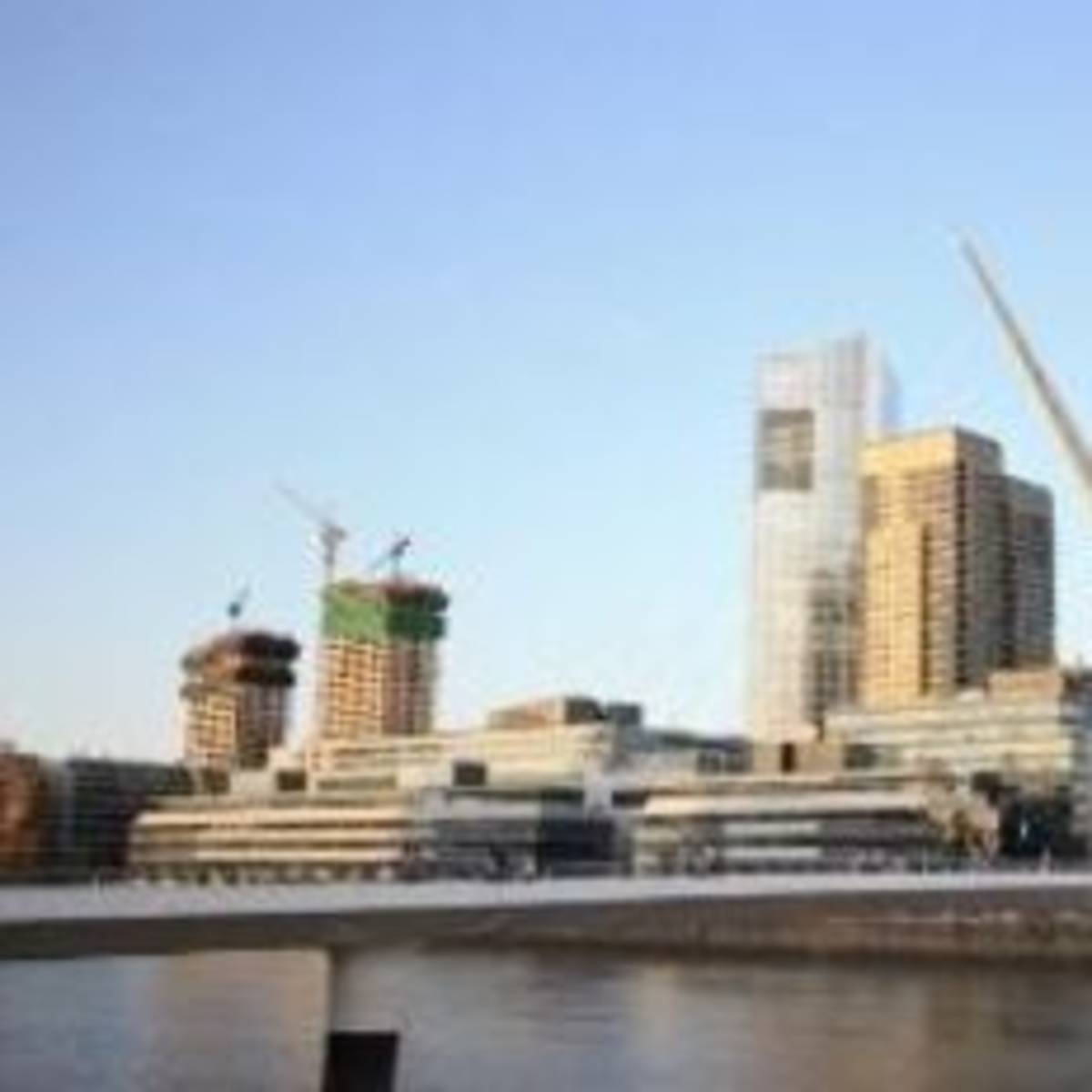 A bridge spanning a river with towering buildings in the backdrop.