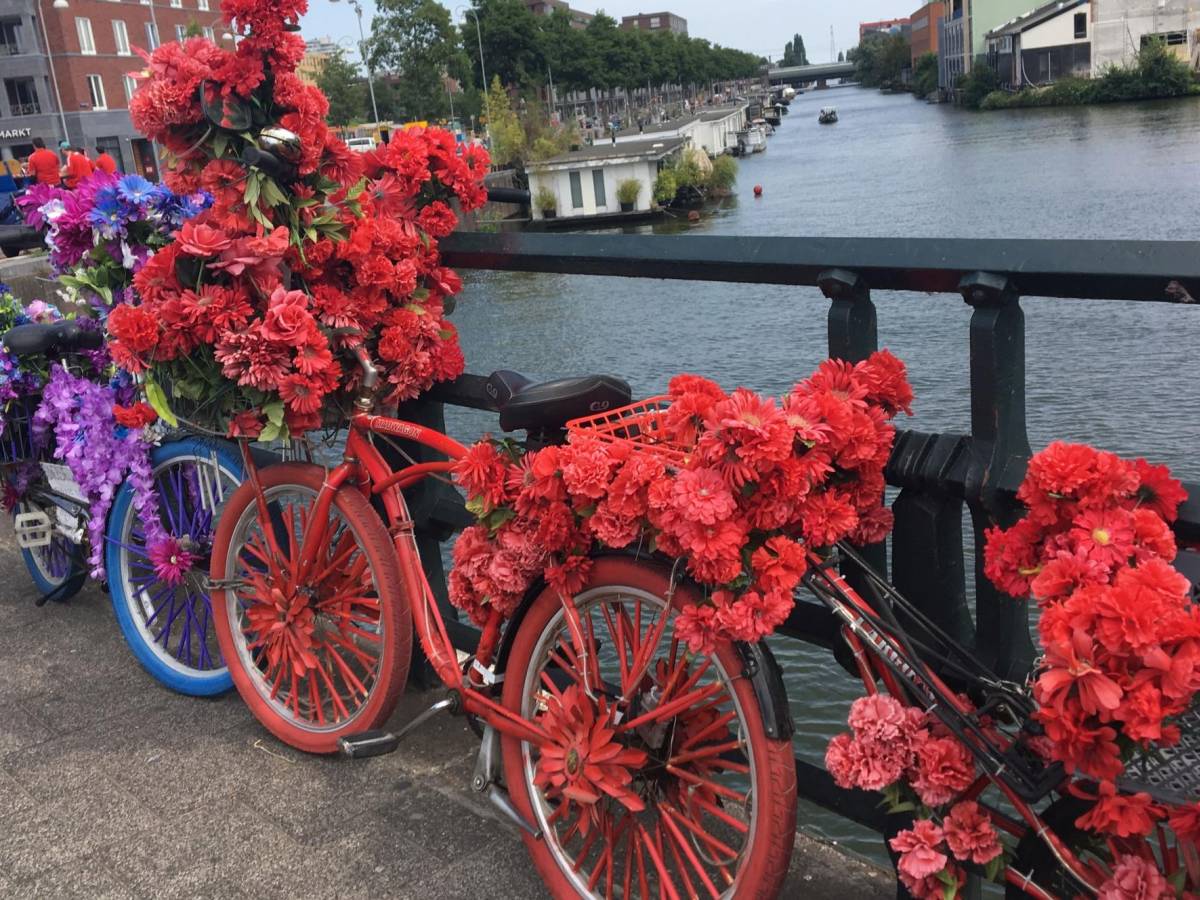A colorful bike full of flowers leans against a bridge in Amsterdam.