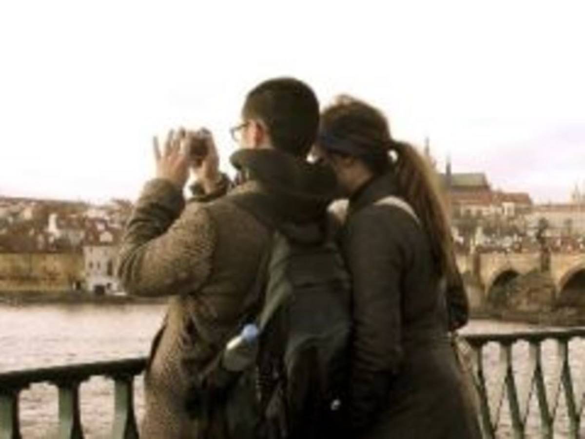 A couple capturing cityscape photos from a bridge, enjoying the scenic view together.