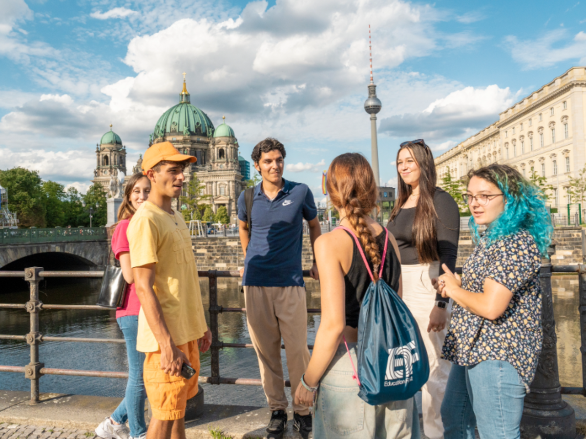 A group of EF students stand by the river in Berlin, with the Berlin Cathedral and TV Tower in the background.