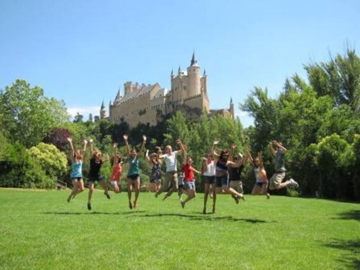 A group of people joyfully jumping in front of a majestic castle.