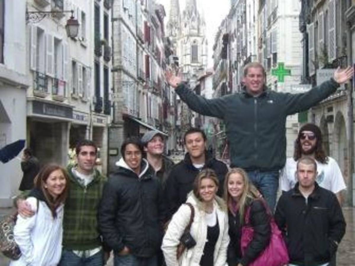 A group of people smiling and posing for a photo in a charming narrow street.