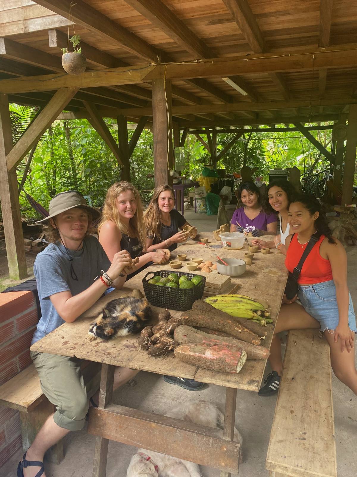 A group sitting around a rustic table with food smiles for the camera.