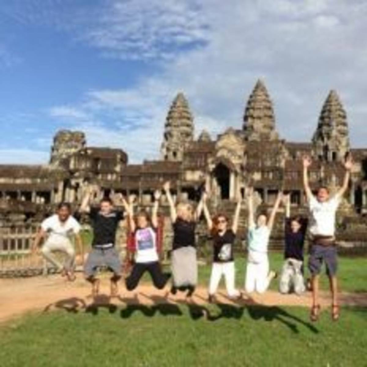 A joyful group of people leaping in front of a majestic ancient temple