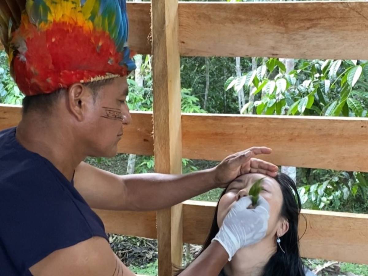 A man in headdress administers tobacco medicine up the nosal passage of a woman.