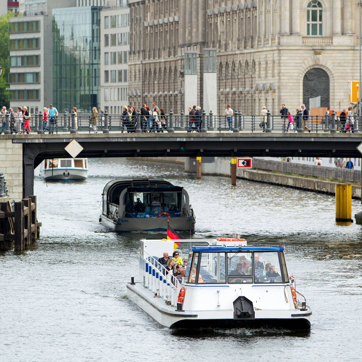 A pedestrian bridge over a river with boats.