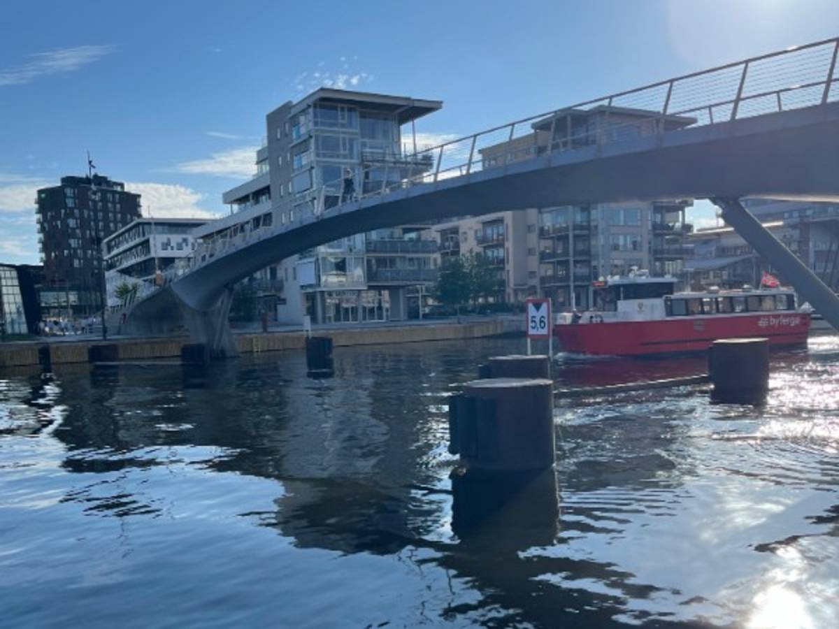 a red ferry boat travels underneath a bridge on the river