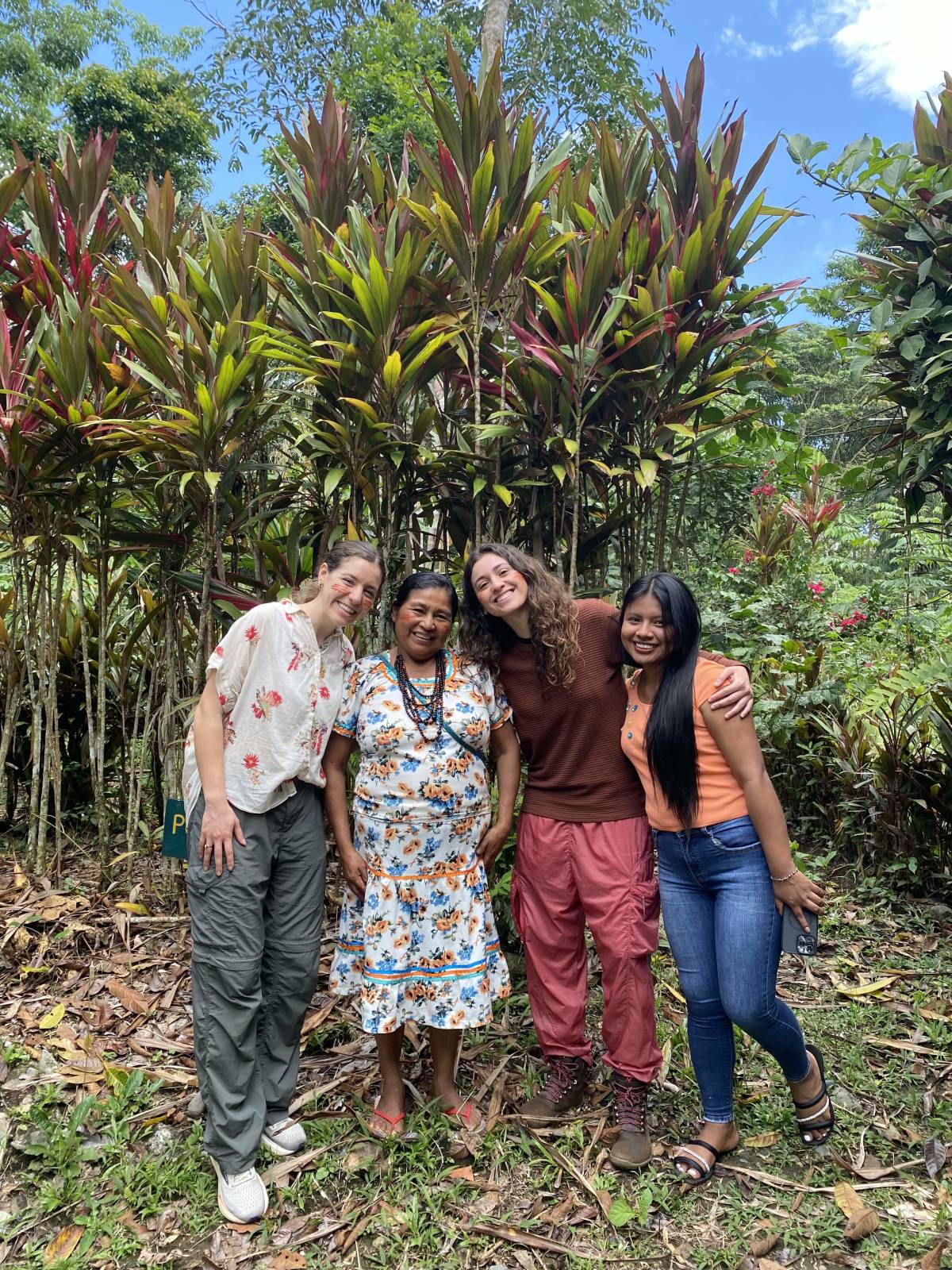 A smiling group with a woman in traditional Kichwa clothes. 