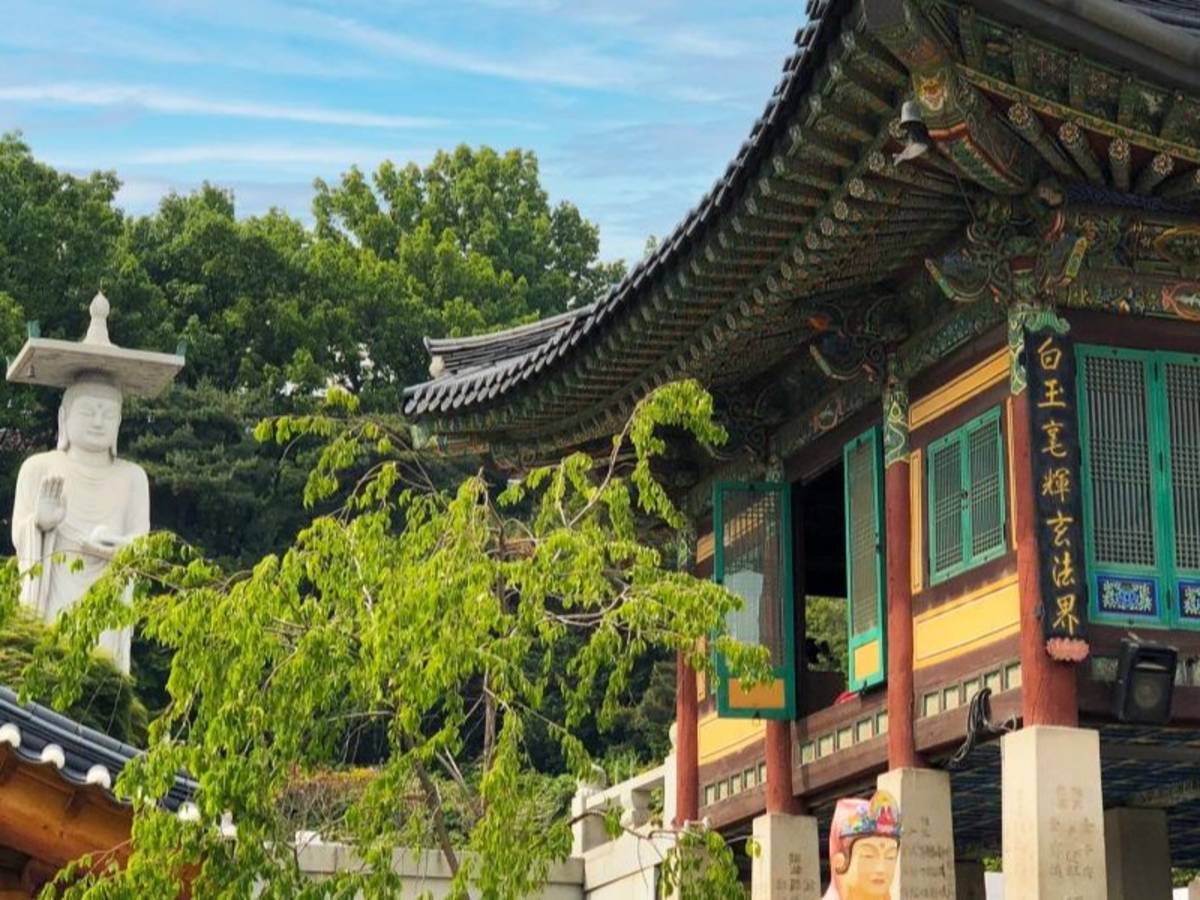 A structure within Bongeunsa Temple and a Buddha statue on a sunny summer day.