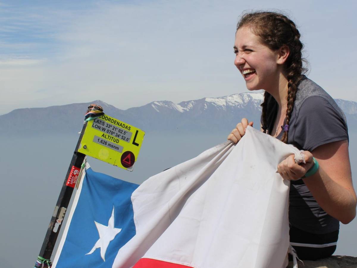 a student in the mountains with a Chilean flag