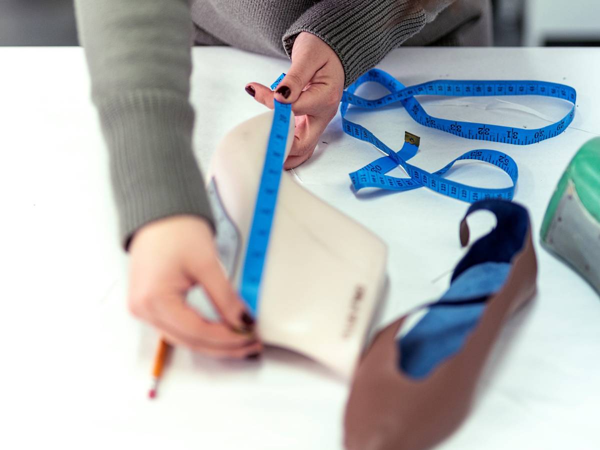 A student measuring for shoe design with a long blue tape
