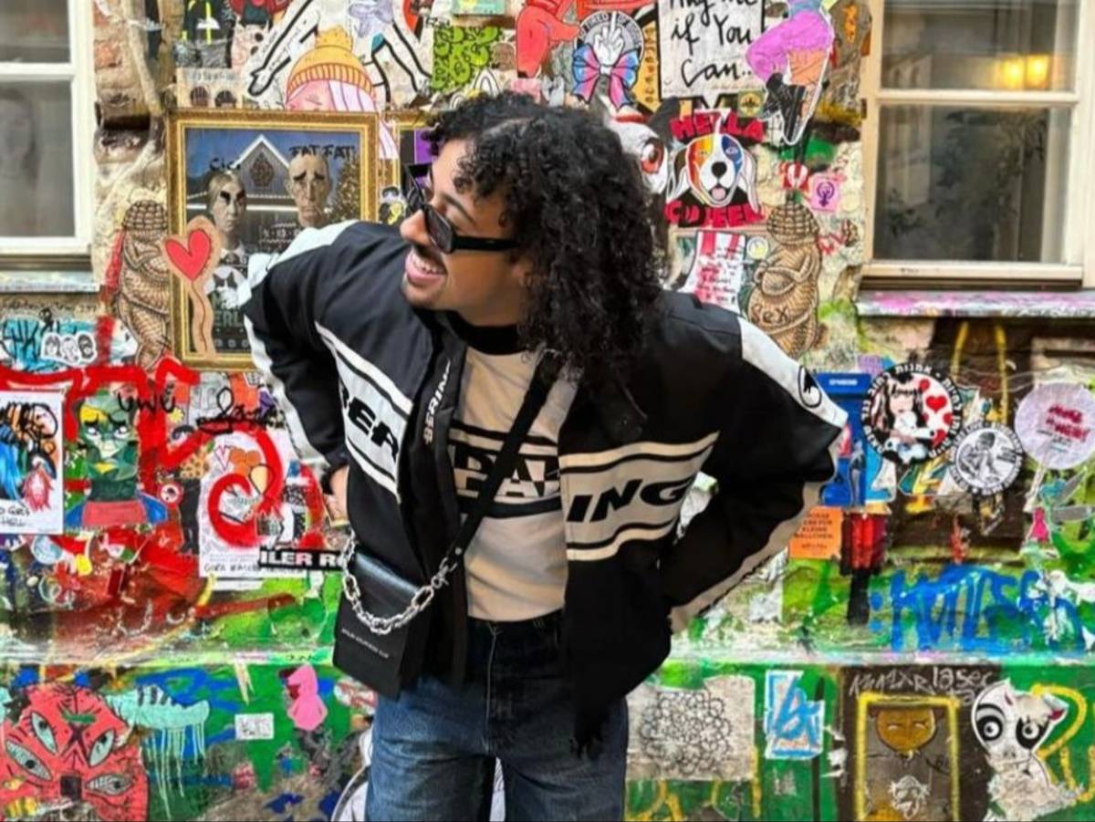 A student poses in front of a colorful, heavily graffitied wall in Berlin, Germany.