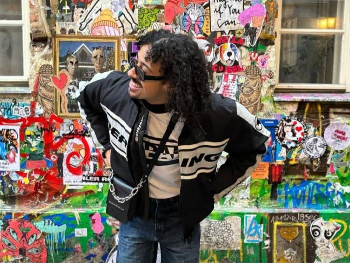 A student poses in front of a sticker and graffiti-covered wall in Berlin, Germany.
