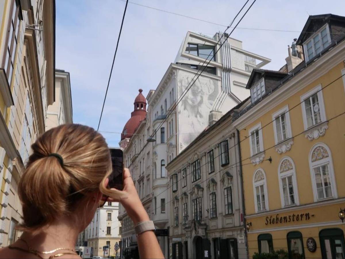 A student snaps a picture of a historical yellow building in Vienna, Austria.