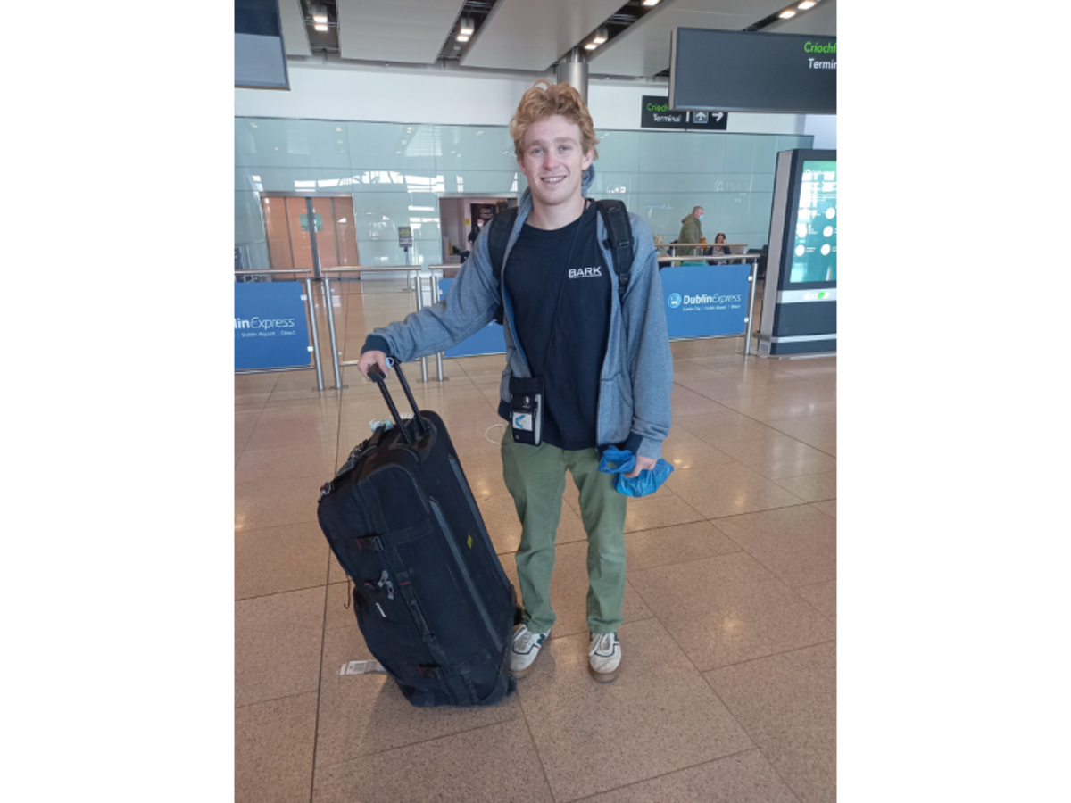 a traveler in an airport with a large rolling duffel bag
