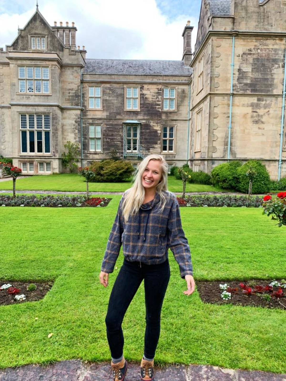a woman standing in front of the Muckross House, a famous 19th-century Victorian mansion in Ireland