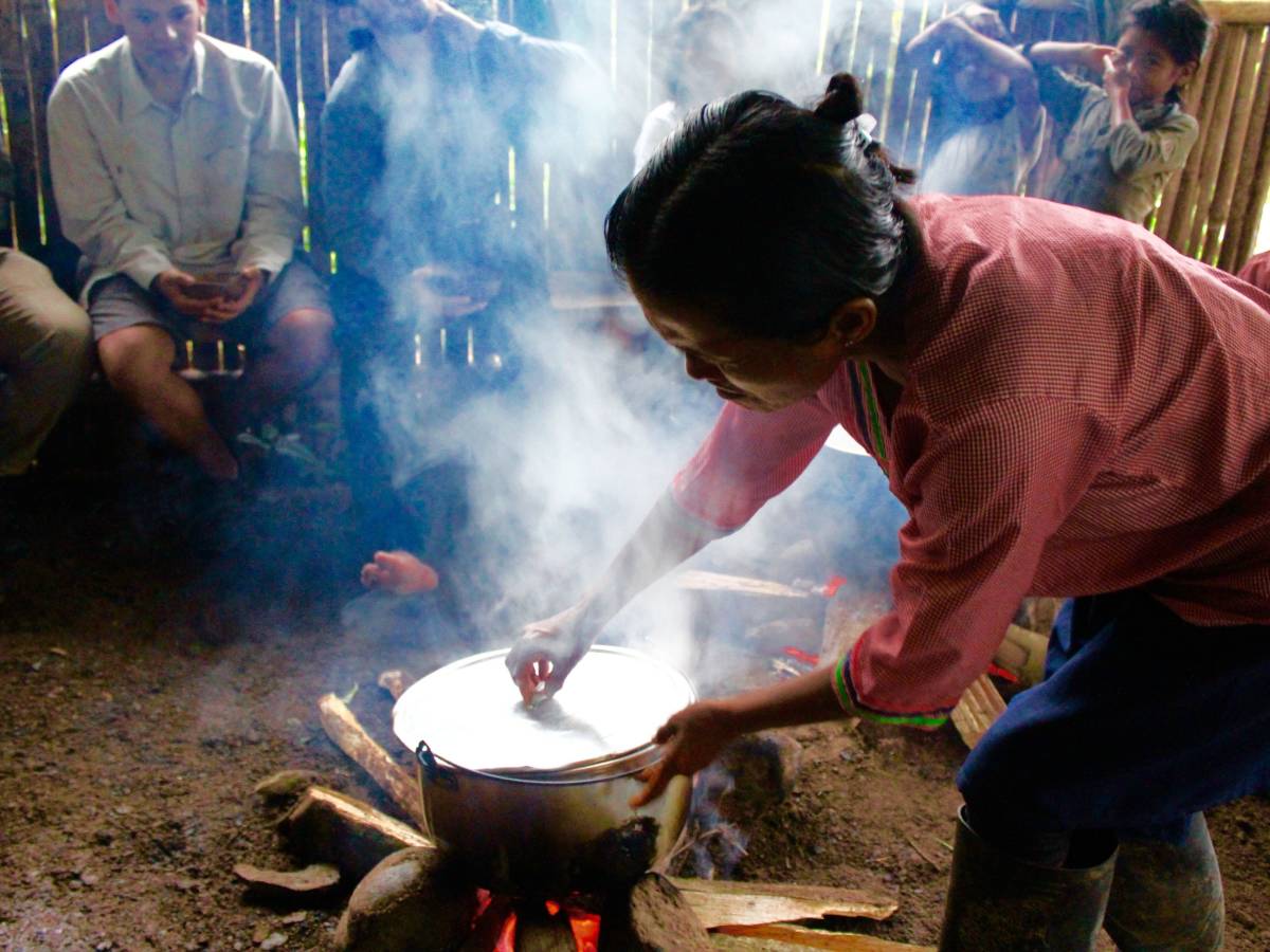 A woman stirs a pot over a fire.