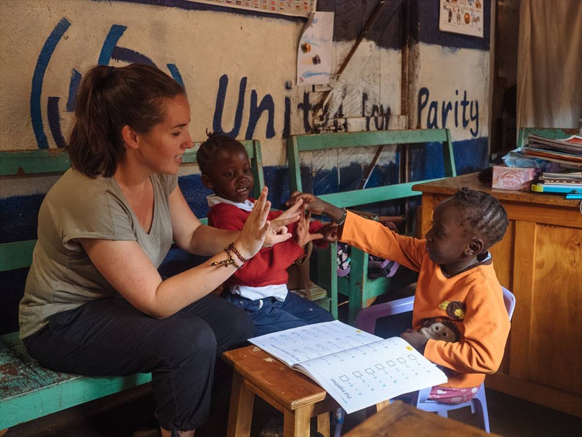 a woman teaching two local children