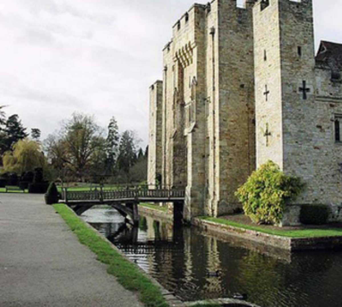 Castle with bridge over river, surrounded by lush greenery.