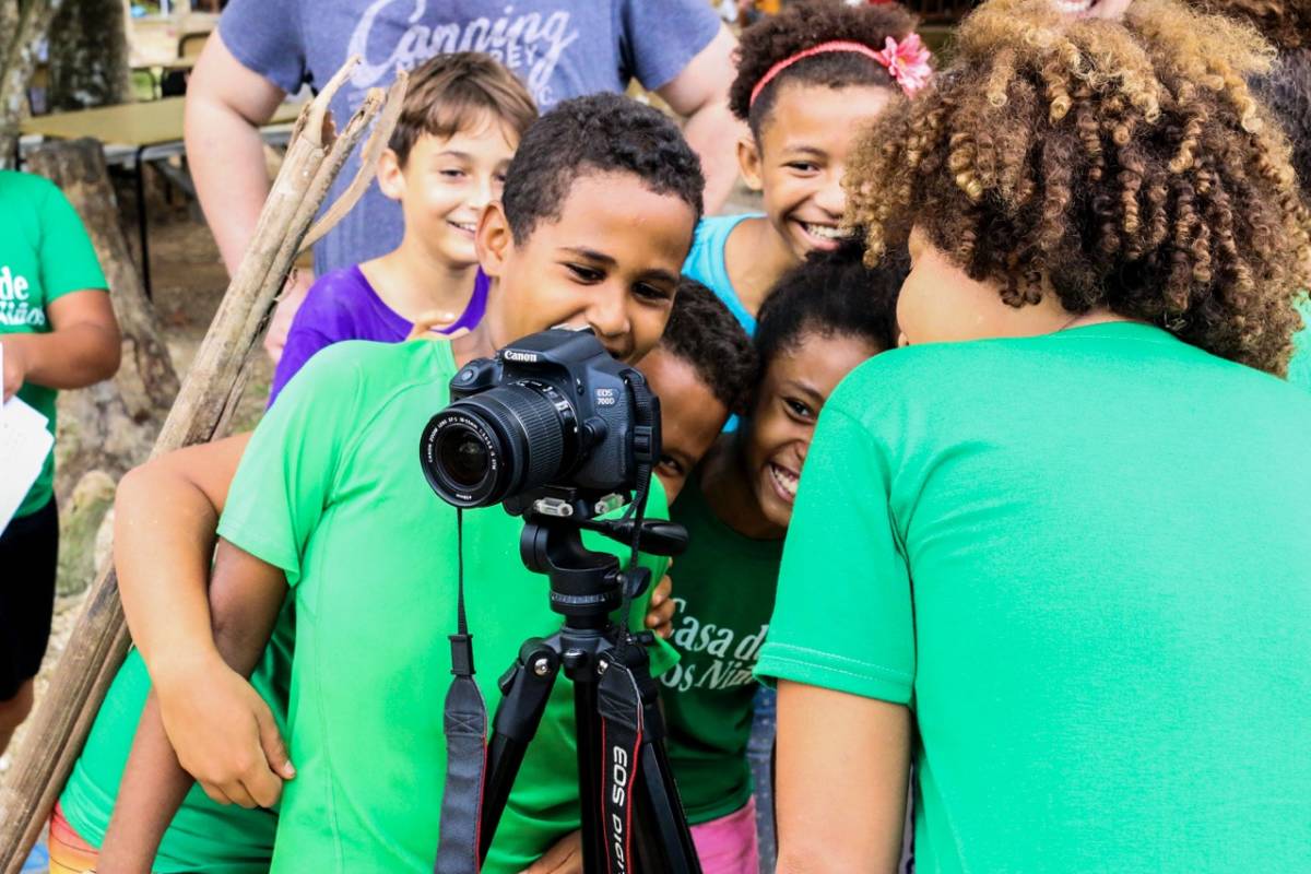 children and intern looking at the back of a camera on a tripod