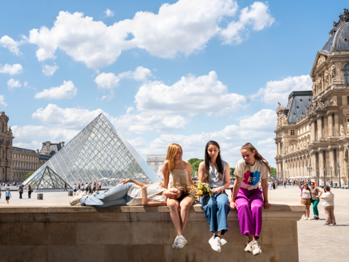 EF Paris students sitting together near the Louvre Pyramid, enjoying the sunshine and conversation.