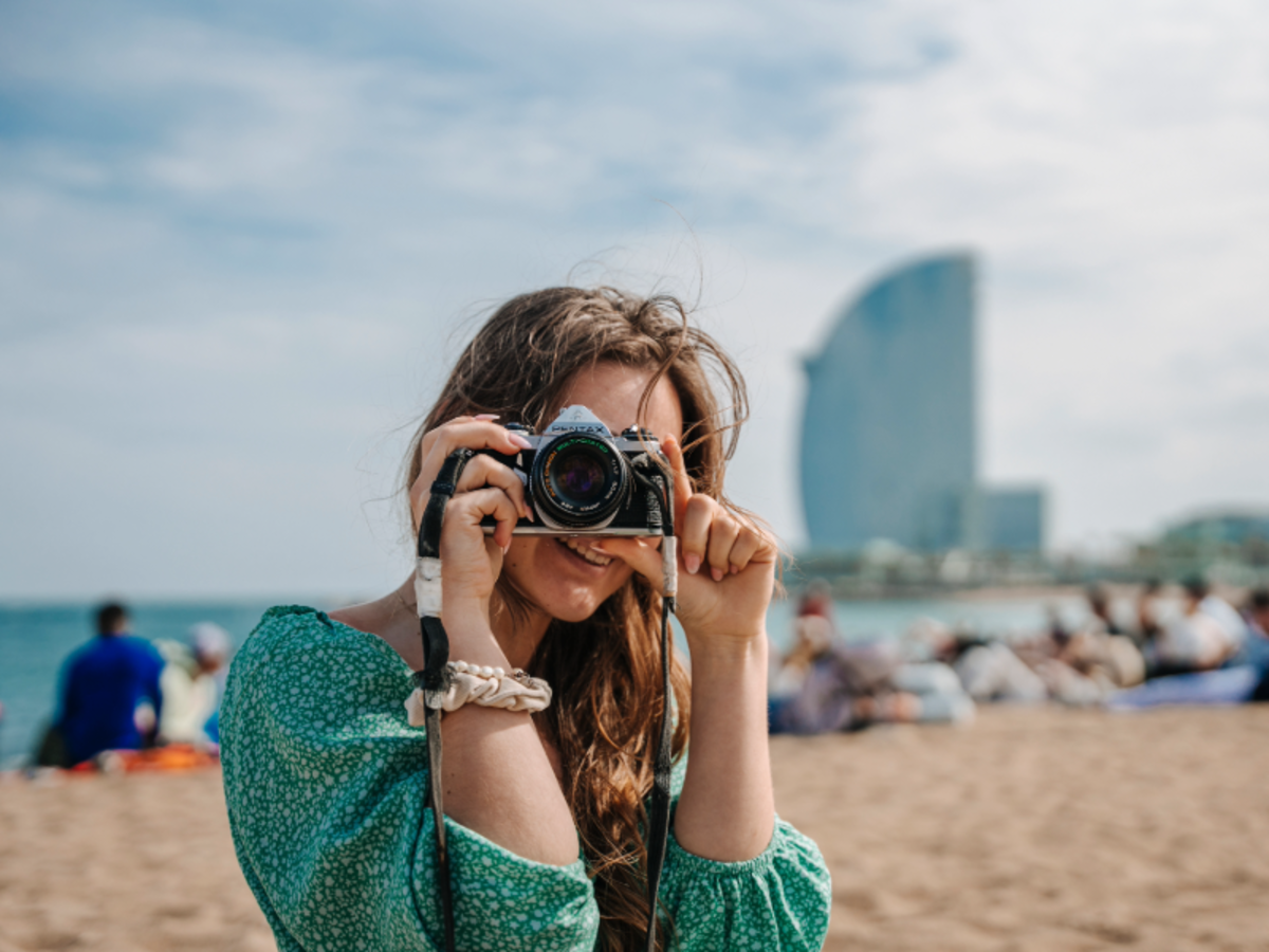EF student taking a photo on the beach in Barcelona, with the W Hotel visible in the background.