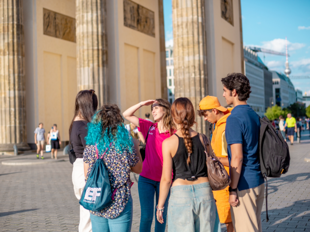 EF students and staff gather near the Brandenburg Gate in Berlin, listening to a guide during a cultural activity.