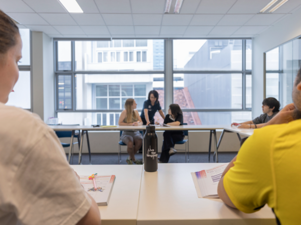 EF students in a classroom in Singapore studying Mandarin with their teacher, books and notes open on the desks.