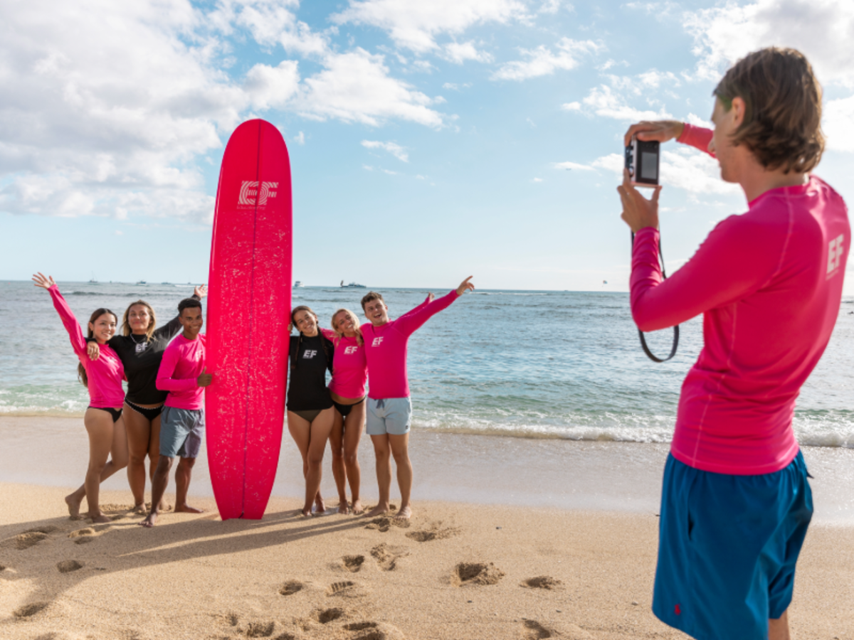 EF students pose with a surfboard on the beach in Playa Tamarindo, Costa Rica, after a surfing lesson.