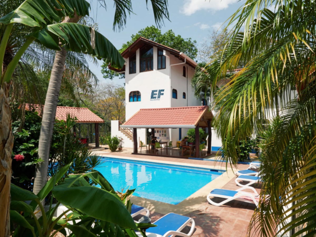 EF Tamarindo campus in Costa Rica with a pool surrounded by palm trees, lounge chairs, and tropical buildings where students live and study abroad.