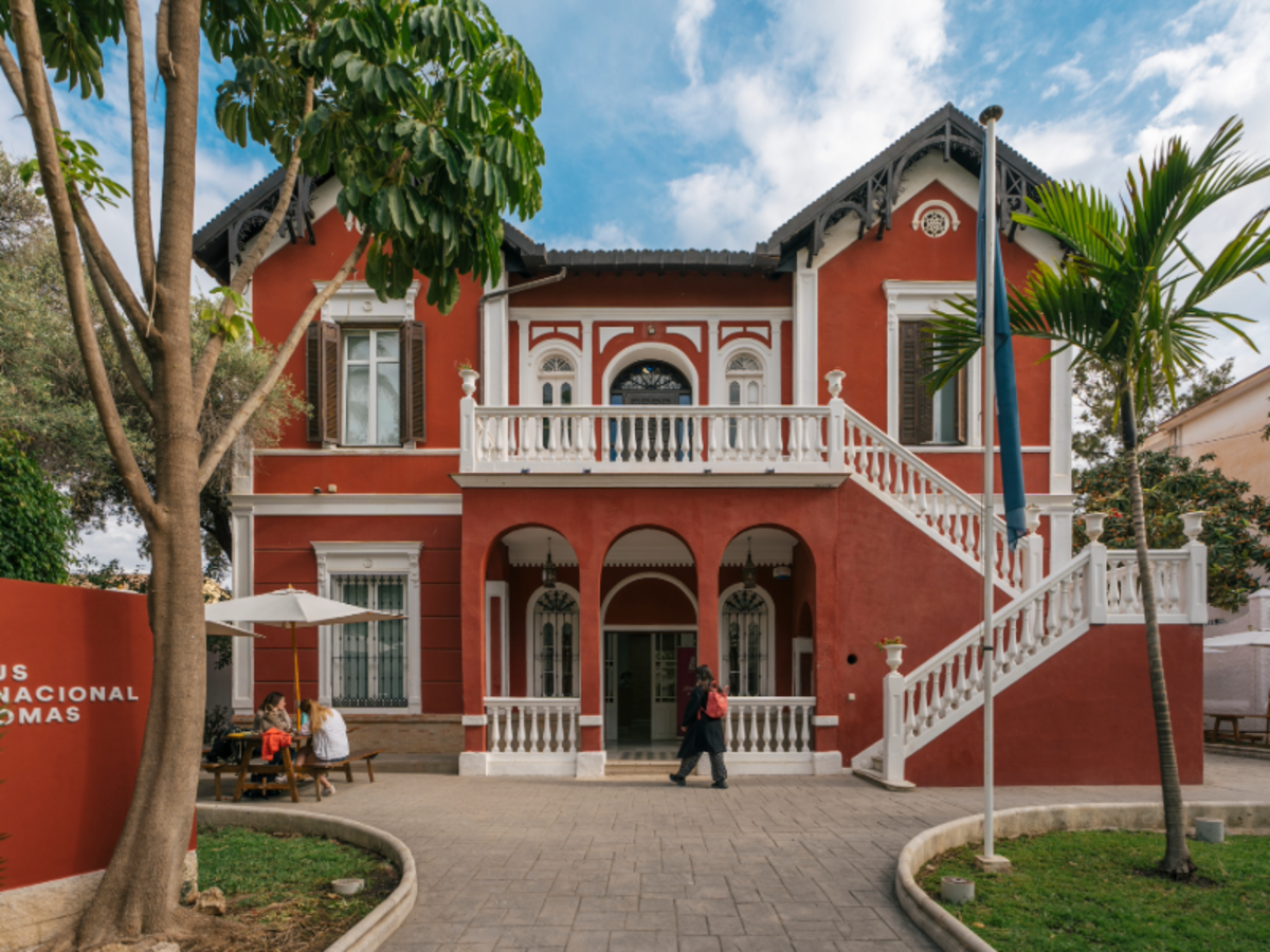 Exterior of EF Malaga school, a historic red villa with white balconies, palm trees, and students entering the building.