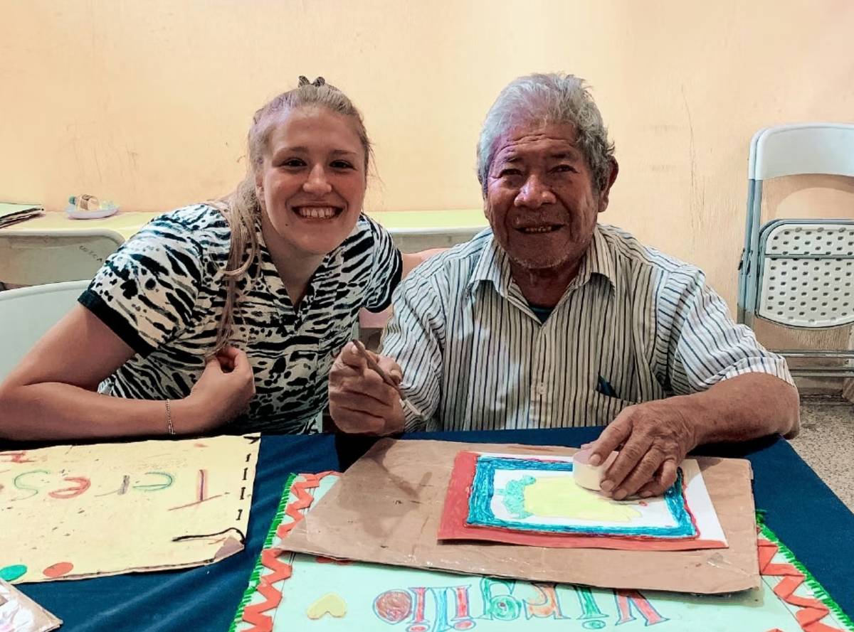 Female Volunteer assisting an Senior Citizen Painting