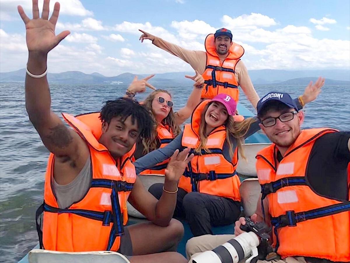 five people wearing life vests on a boat ride