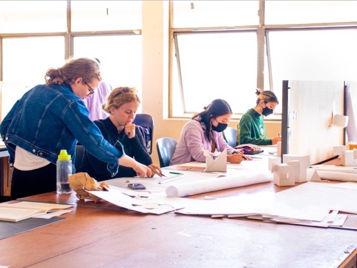 Four students working on designs at desk