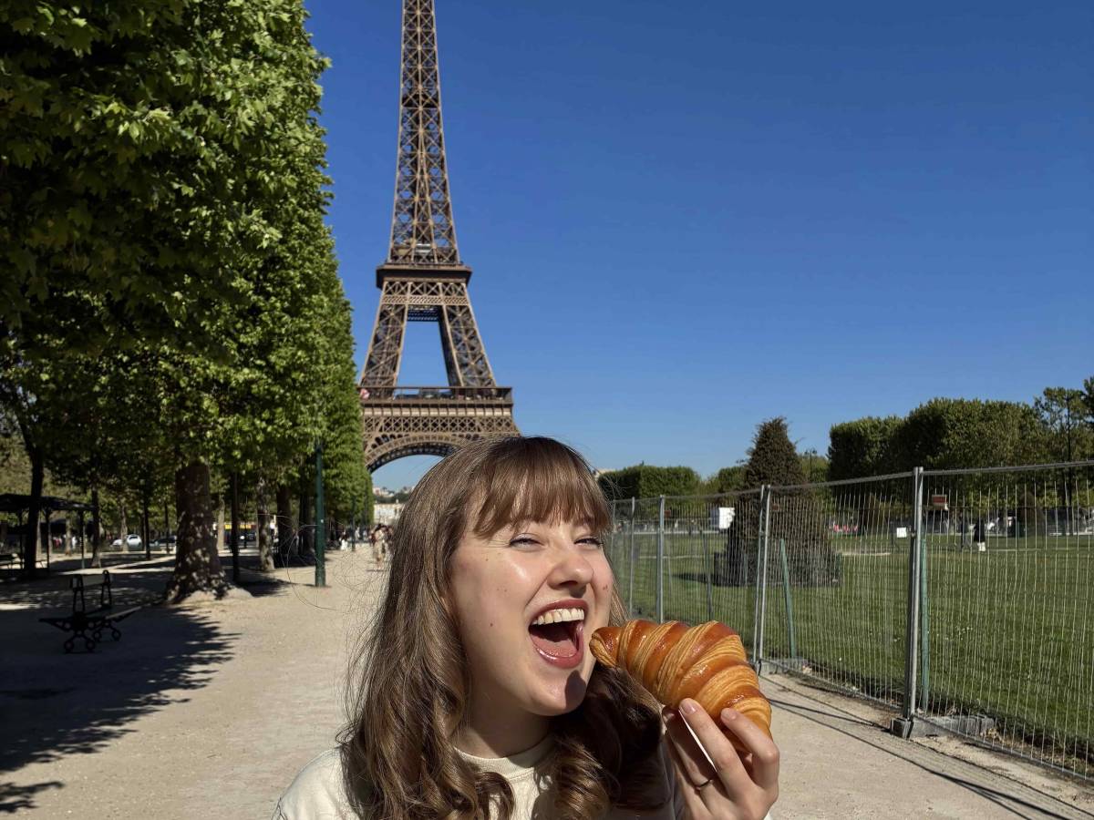 Girl eating crosissant beside Eiffel Tower