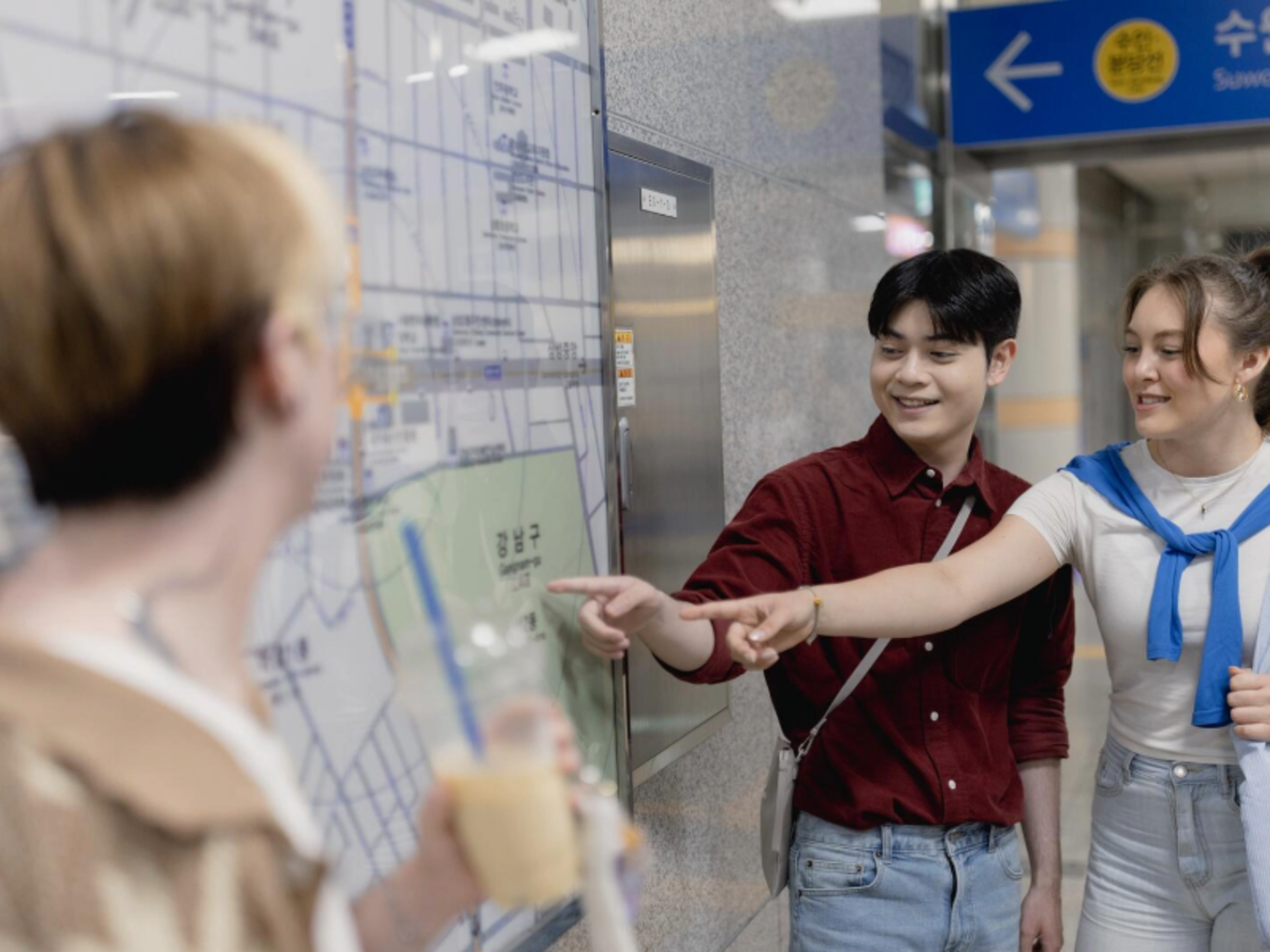 Group of EF Gap Year students looking at a subway map in Seoul, South Korea, smiling and planning their route while experiencing city life and local culture.