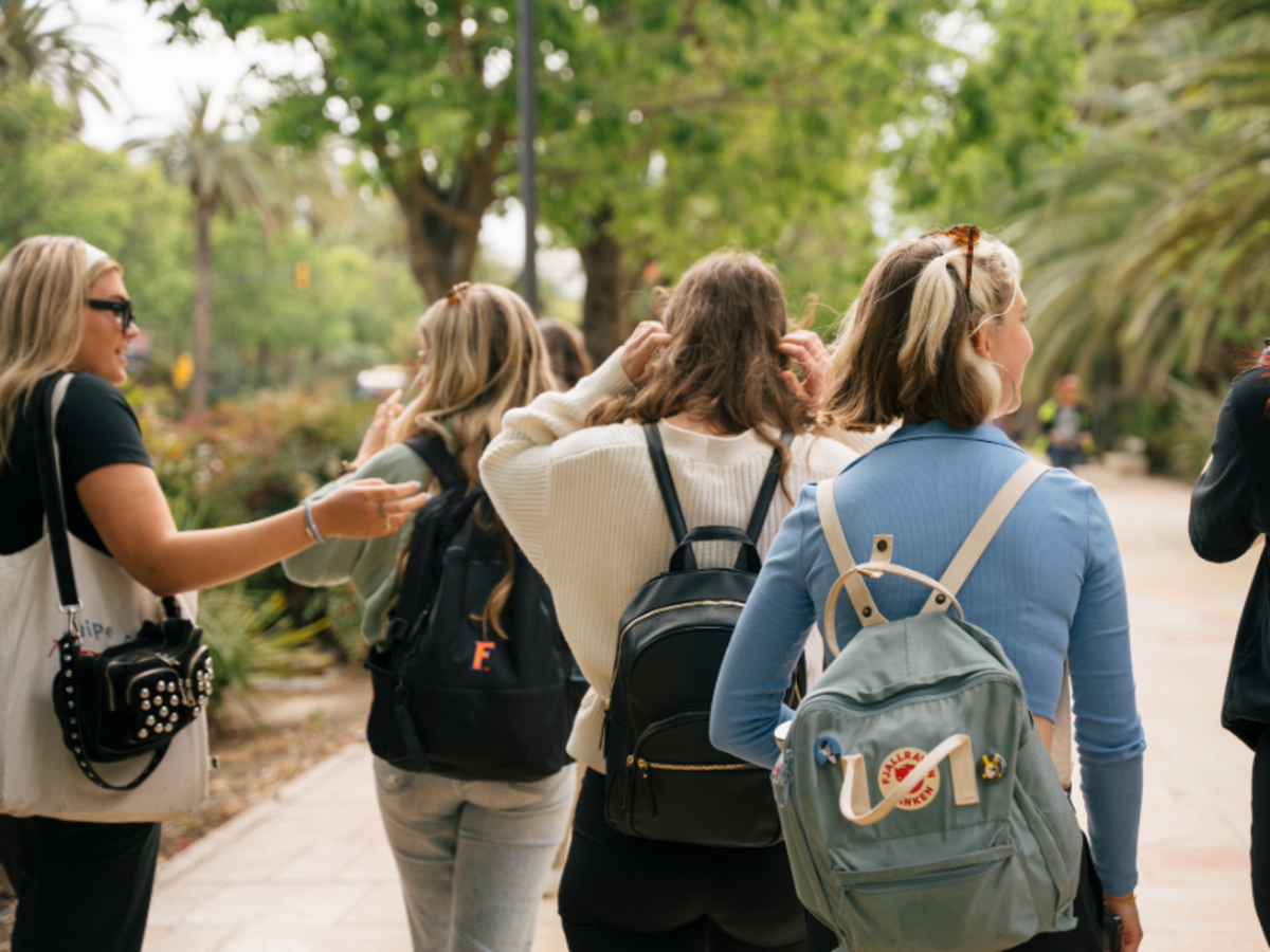 Group of EF Malaga students walking together through a green park, carrying backpacks and chatting outdoors.