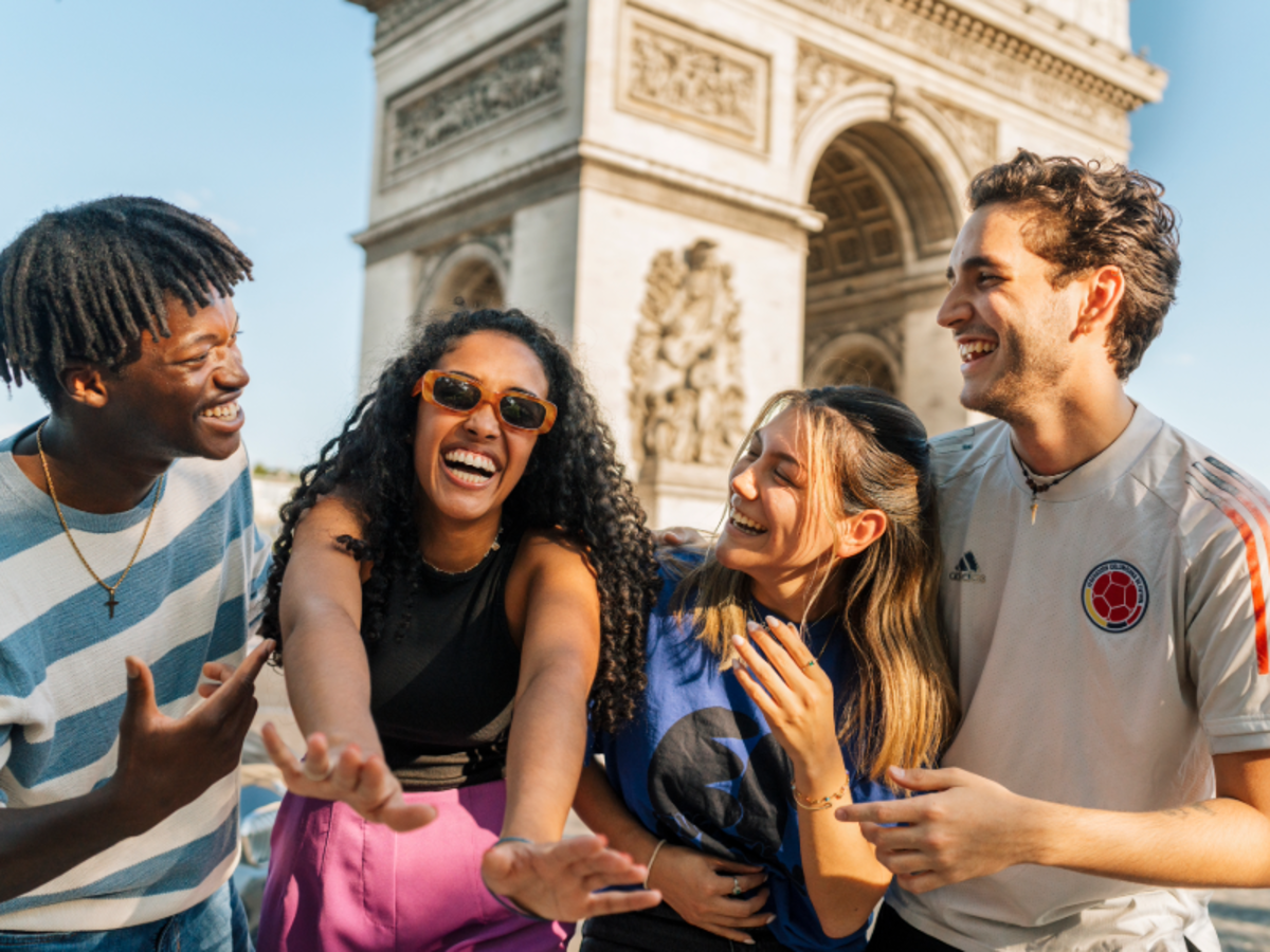 Group of EF students laughing together in front of the Arc de Triomphe in Paris on a sunny day.