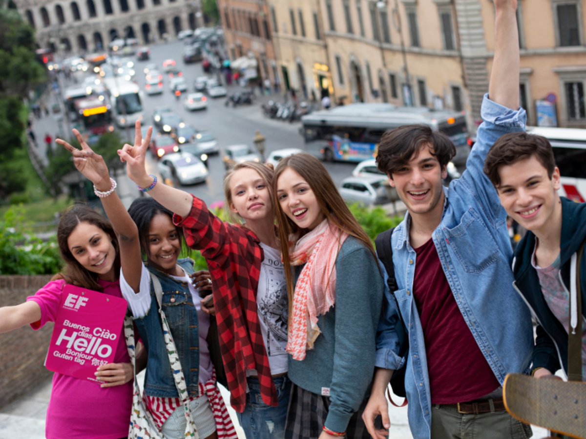 Group of EF students smiling and posing together in Rome with the Colosseum visible in the background.