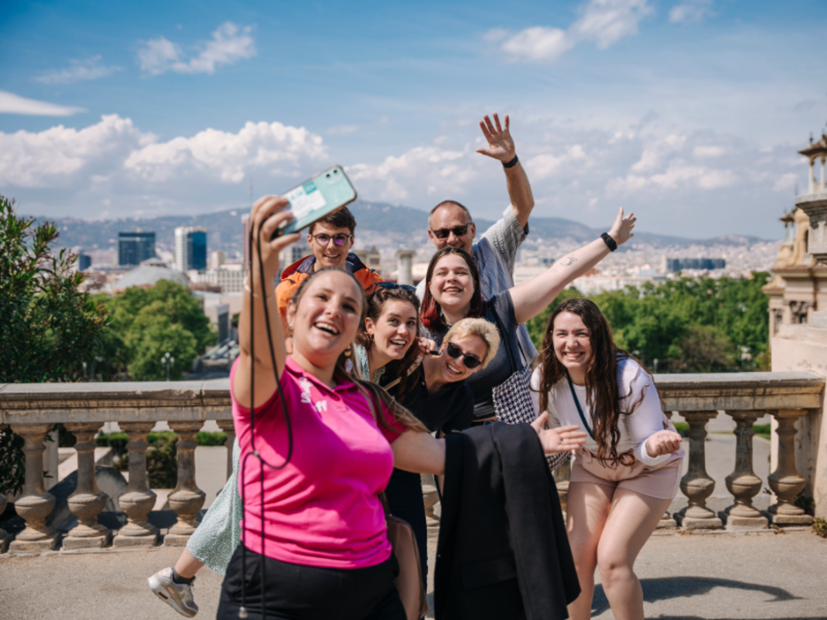 Group of EF students taking a cheerful group selfie with views of Barcelona in the background.