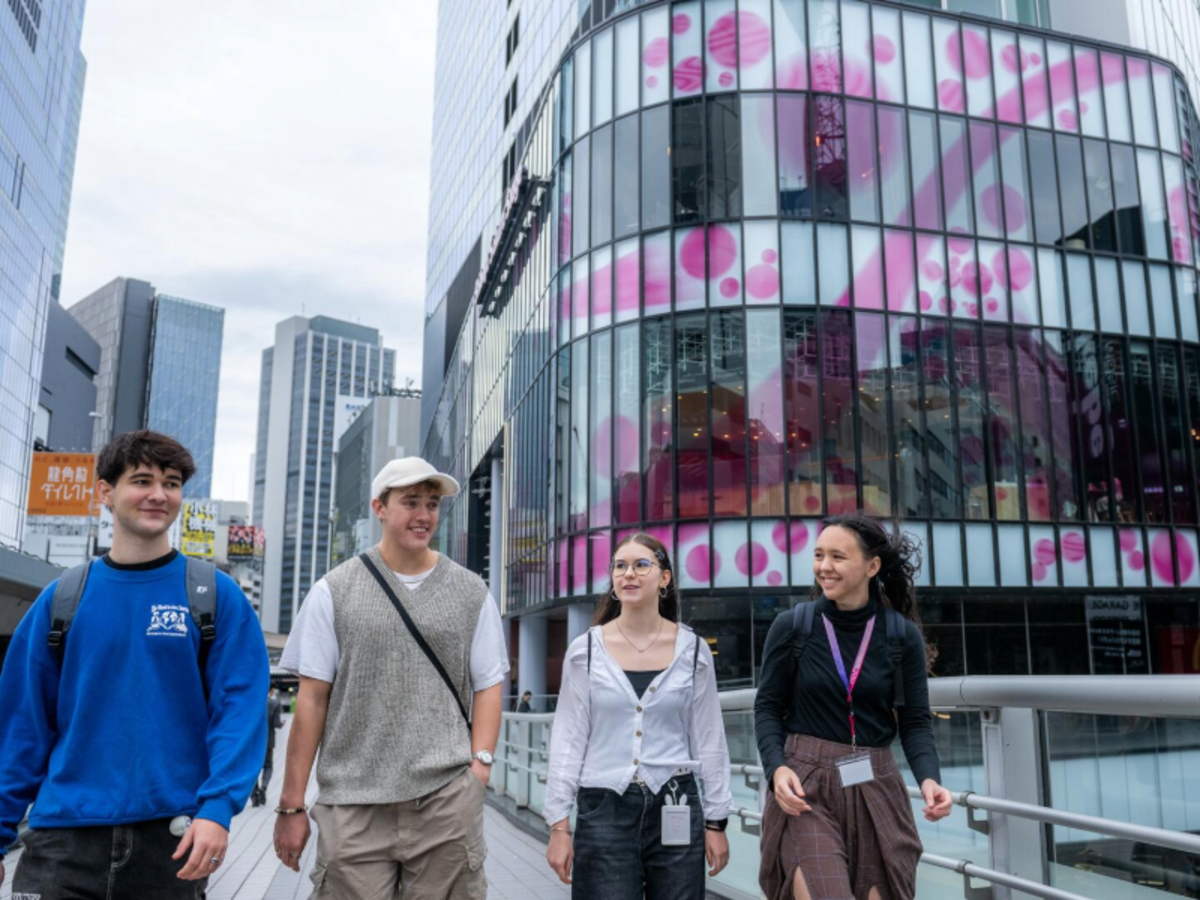 Group of EF students walking together in a modern city district of Tokyo, surrounded by tall buildings and colorful storefronts.