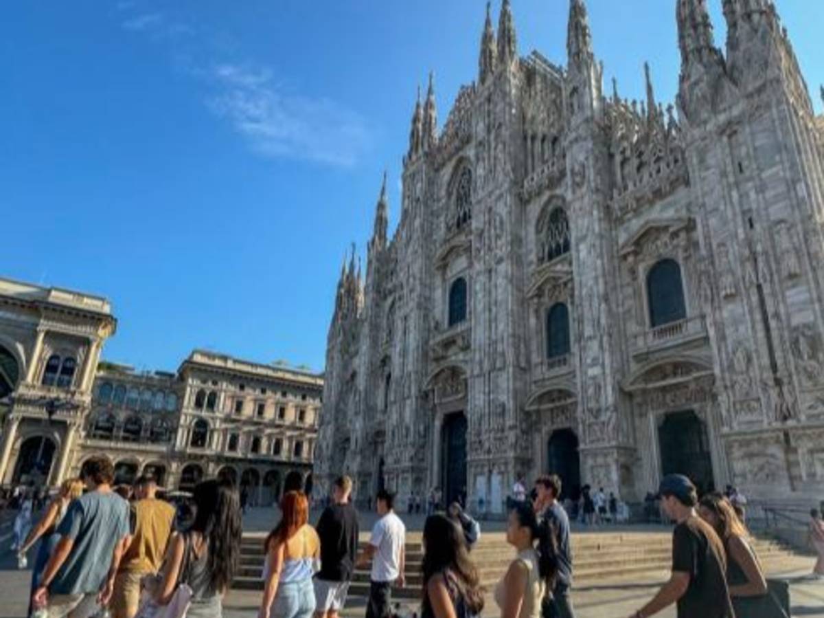 Group of students walking past the Duomo in Milan on a sunny morning