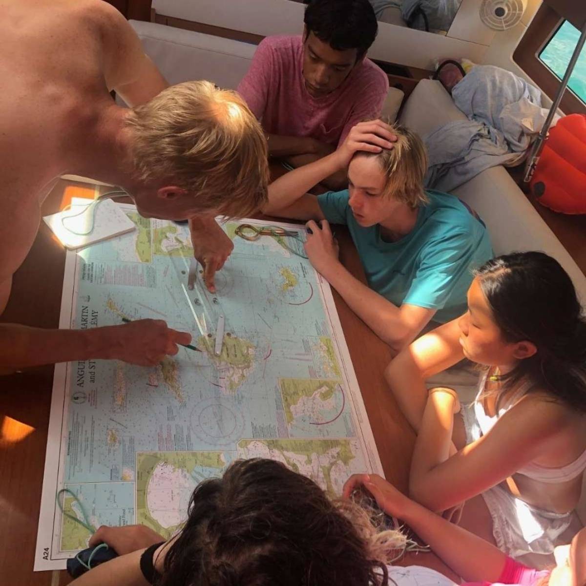 Group of teens plotting course in monohull.
