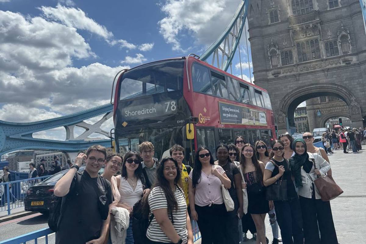 High school students posing by double-decker bus in London